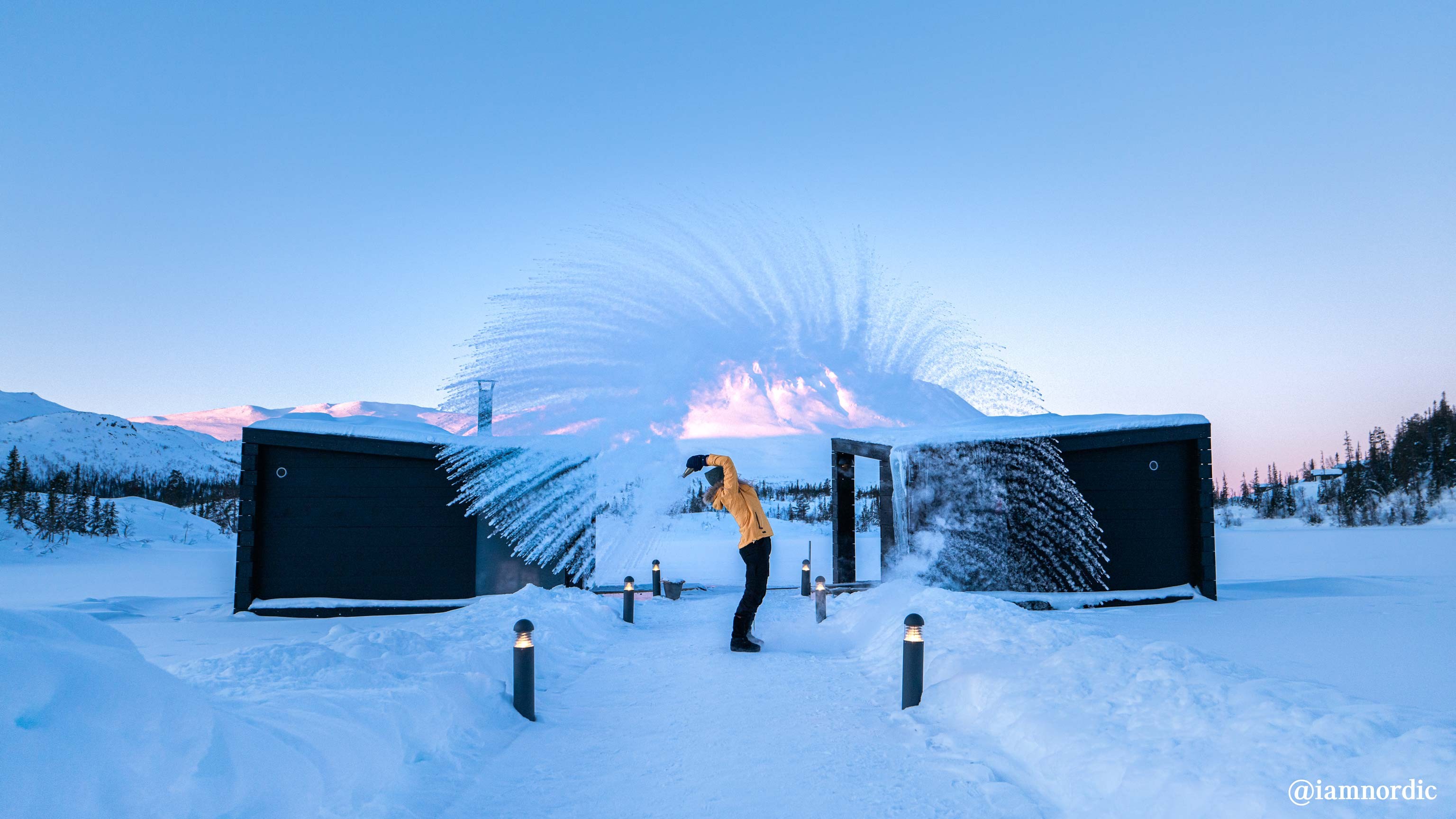 A man in a yellow jacket playing in the snow in the countryside.